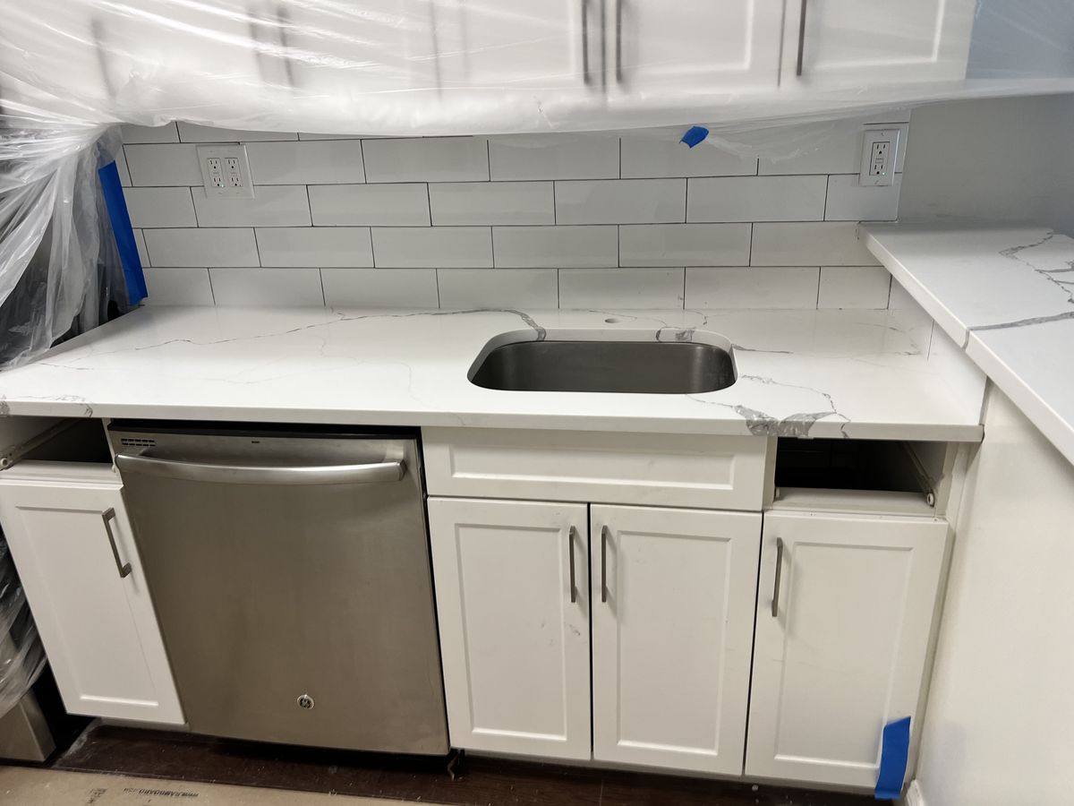Kitchen countertop installation with white cabinets and tile backsplash