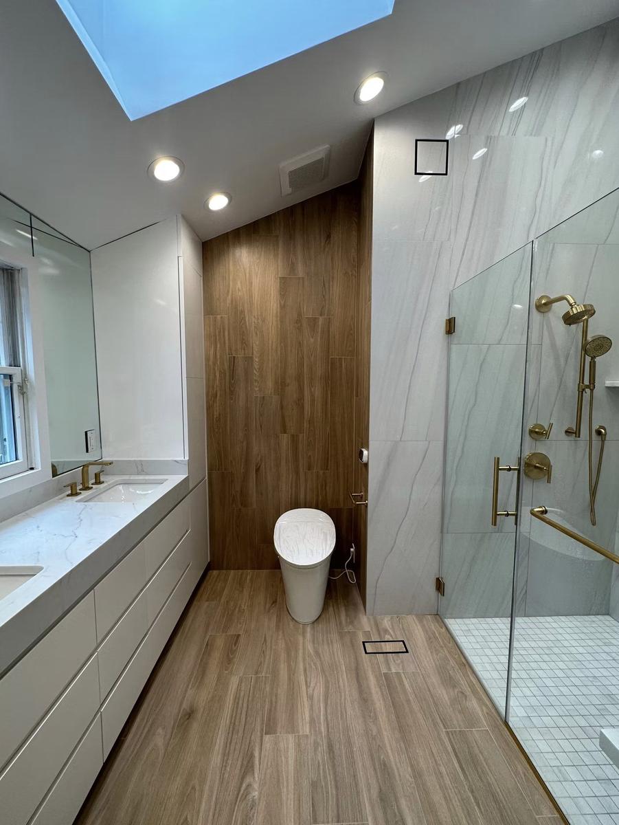 Full view of luxury bathroom renovation featuring custom walnut vanity, frameless glass shower, and marble tile by Lion Construction Management