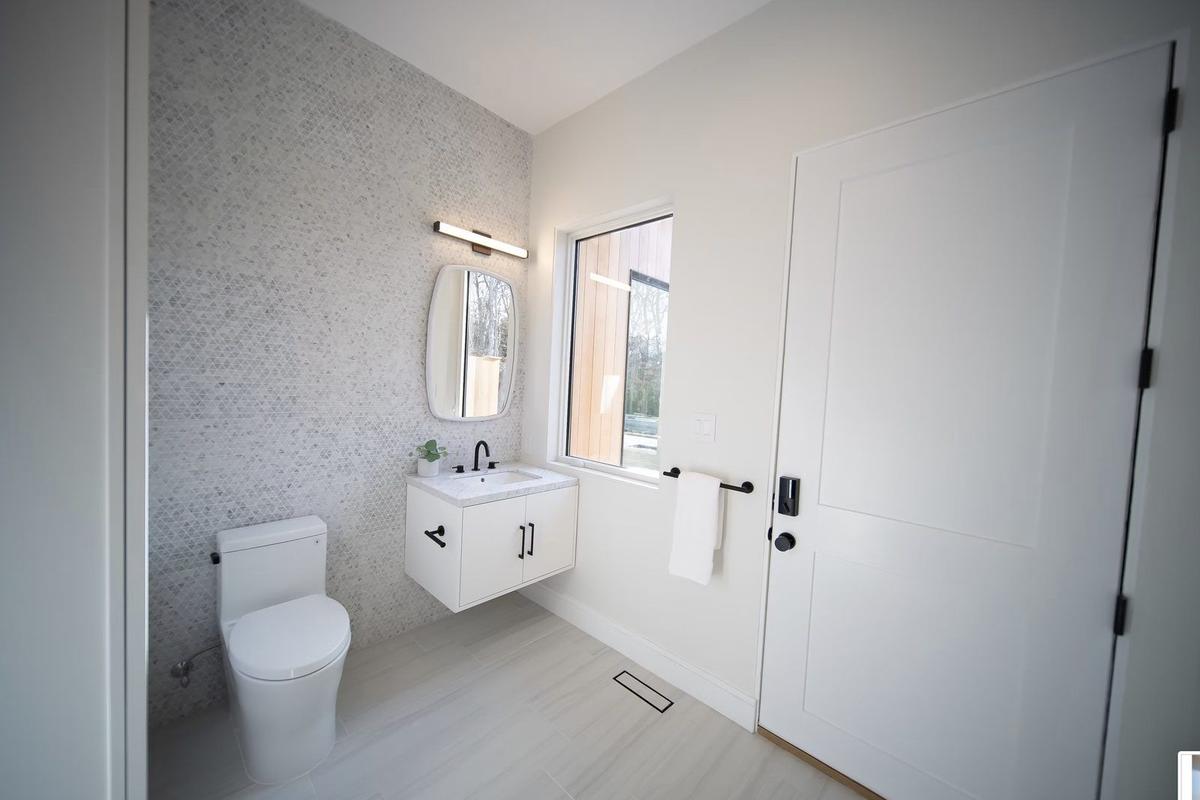 Guest bathroom with custom tile, floating vanity, and frameless glass shower door