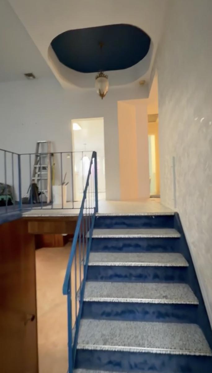 Staircase before renovation with blue carpet and dated iron railing