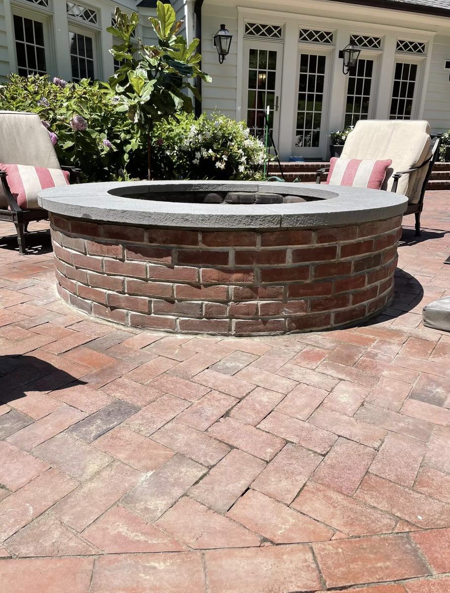 Custom brick fire pit with stone cap in estate outdoor living area
